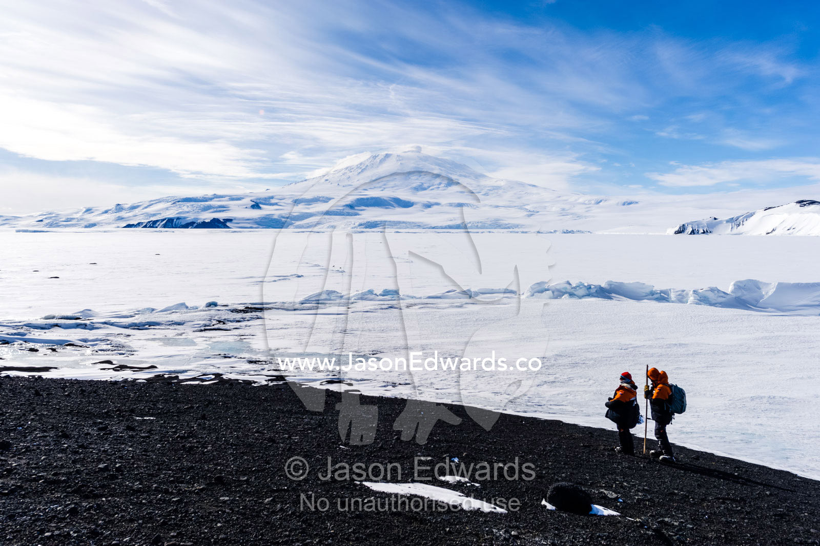Researchers descend a mountain overlooking the frozen sea ice and Mount Erebus. Turtle Rock, Erebus Bay, McMurdo Sound, Ross Island, Antarctica.