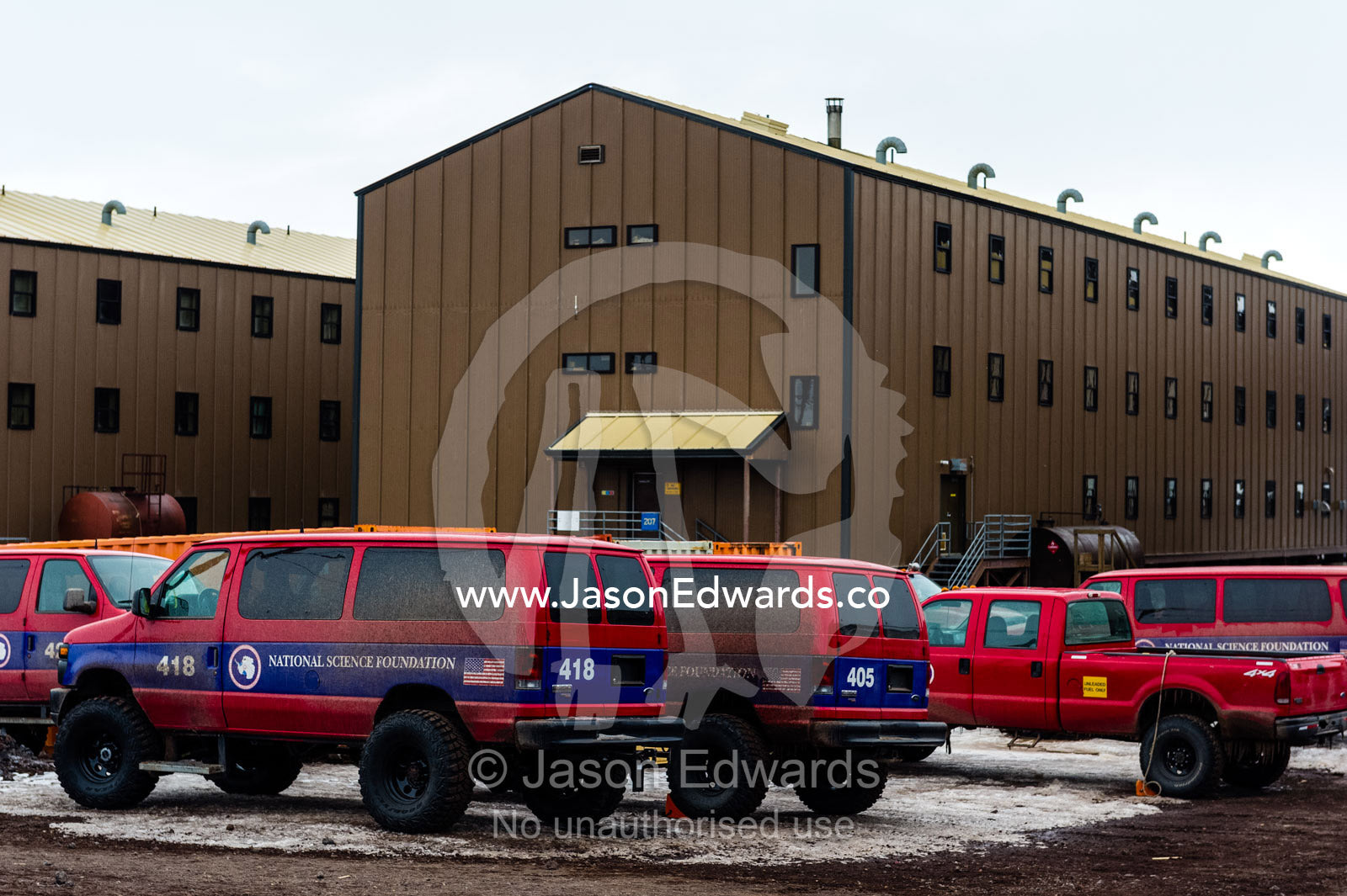 A group of 4wd transport vehicles parked outside the dormitory blocks at McMurdo Station. McMurdo Station, Ross Island, Antarctica.
