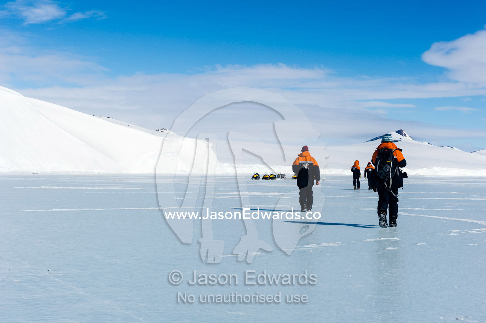 Marine mammal researchers walking across the polished surface of the sea ice. Hutton Cliffs, Erebus Bay, McMurdo Sound, Ross Island, Antarctica.