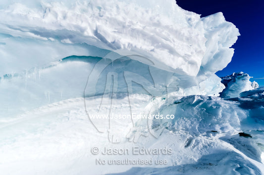 Enormous blocks of ice are pushed skyward along pressure ridges as the sea ice thins and forms melt pools. Pram Point, McMurdo Sound, Ross Island, Antarctica.