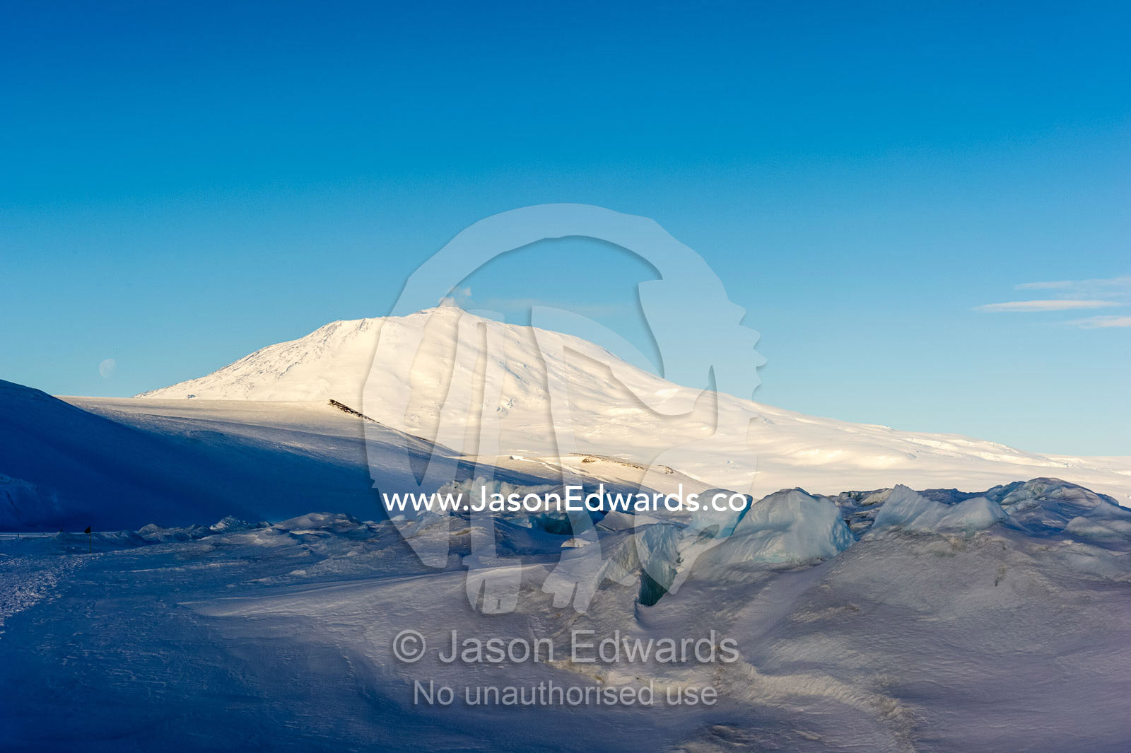 Sunlight illuminates the summit of Mount Erebus the planet's most southerly active volcano. Mount Erebus, McMurdo Sound, Ross Island, Antarctica.