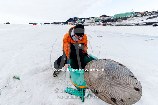 An army engineer descends through the sea ice into a steel observation tube. McMurdo Sound, McMurdo Station, Ross Island, Antarctica.