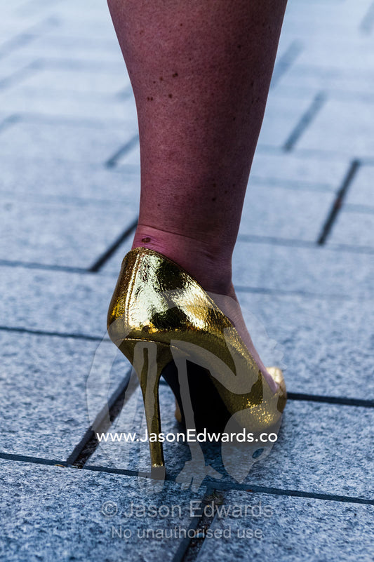 A gold high heel shoe on a sidewalk pavement. Christchurch, New Zealand.