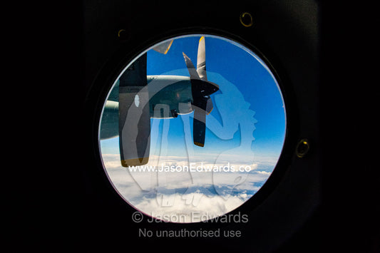 The propeller of a US Air force Hercules through a porthole window flying above the clouds. Southern Ocean, between New Zealand and Antarctica.
