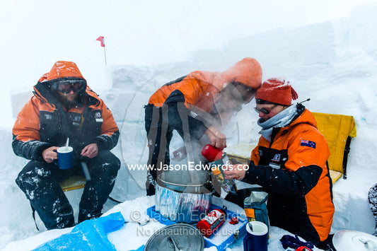 Antarctic base staff eating a meal behind a kitchen wall in a blizzard on the sea ice during a survival course. Windless Bight, Ross Ice Shelf, Ross Island, Antarctica.