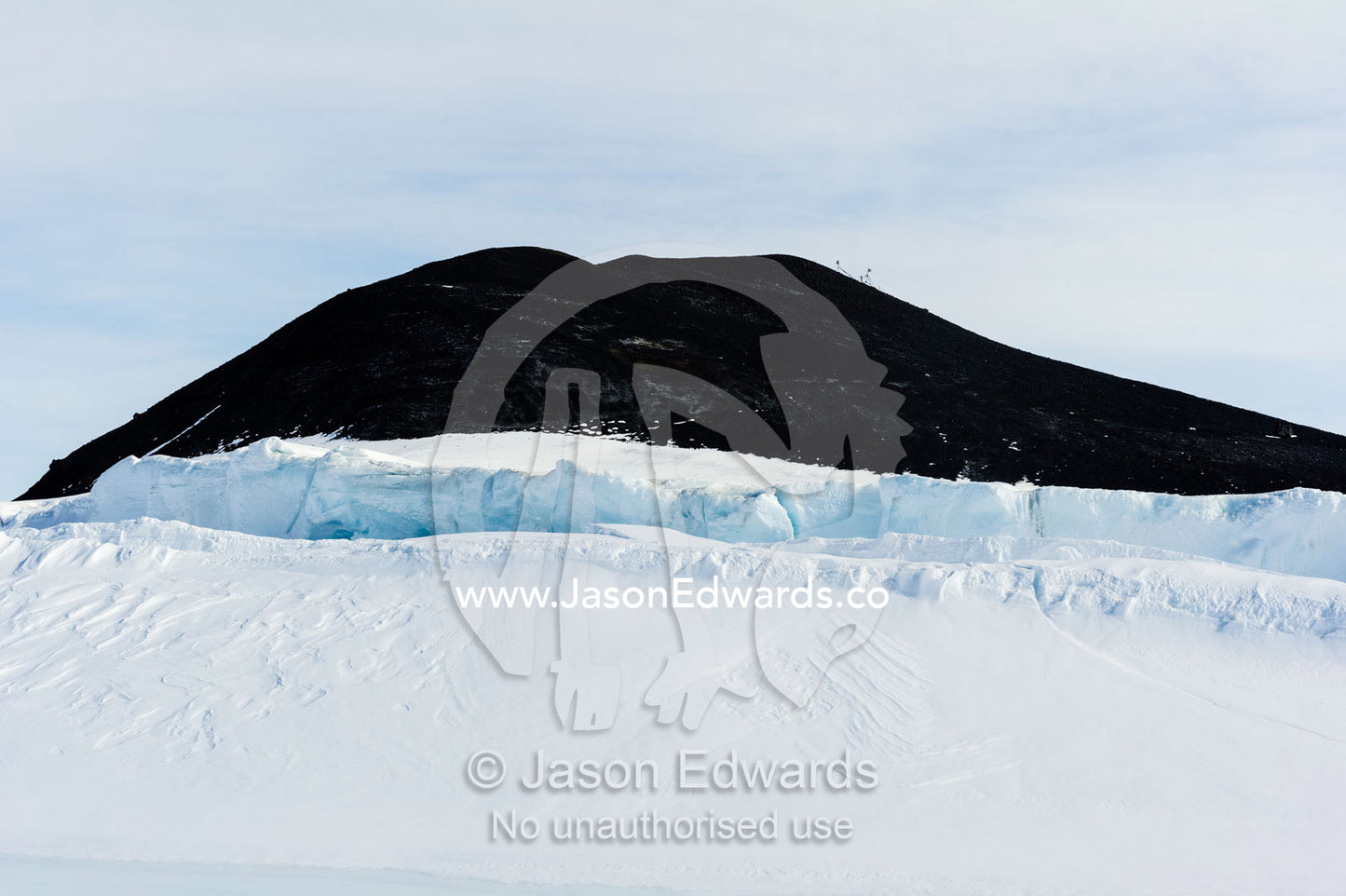 The summit of a volcanic mountain rising above pressure ridges in the sea ice. Turtle Rock, Hutton Cliffs, Erebus Bay, McMurdo Sound, Ross Island, Antarctica.