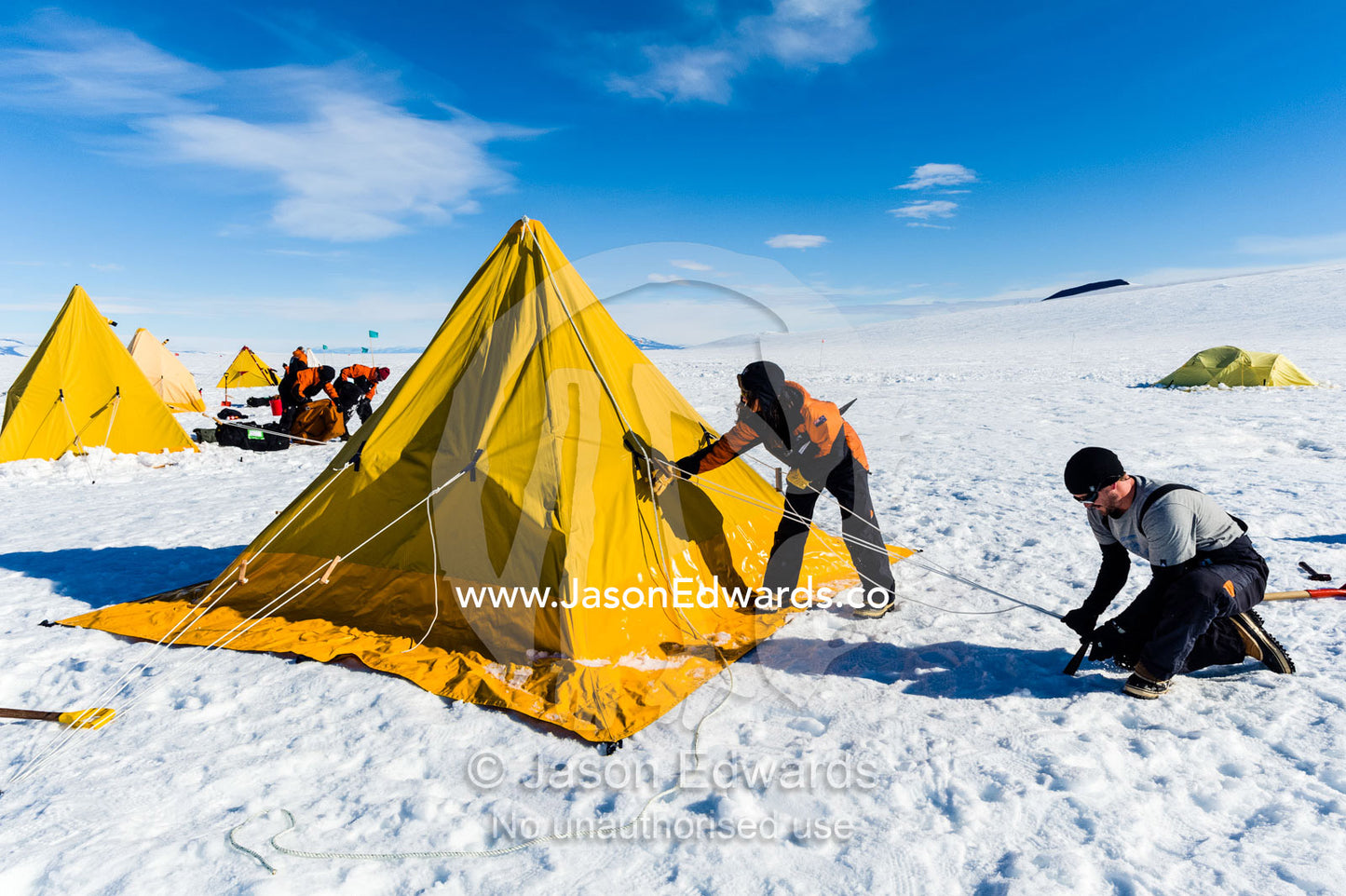 Antarctic base staff pitching a survival tent on the sea ice. Windless Bight, Ross Ice Shelf, Ross Island, Antarctica.