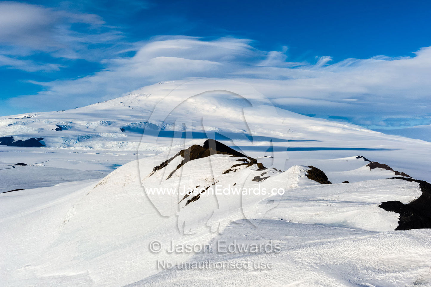 A snow-covered mountain ridge overlooking Mount Erebus an active volcano. Mount Erebus, Breached Cone, Castle Rock, Hut Point Peninsula, Ross Island, Antarctica.