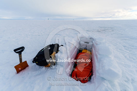 Antarctic base staff in a sleeping bag in a sleeping pit in the sea ice carved from blocks of ice. Windless Bight, Ross Ice Shelf, Ross Island, Antarctica.