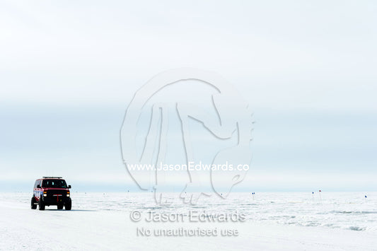 A support vehicle crosses the sea ice to monitor runners in the Antarctic marathon. Ross Ice Shelf, Ross Island, Antarctica.