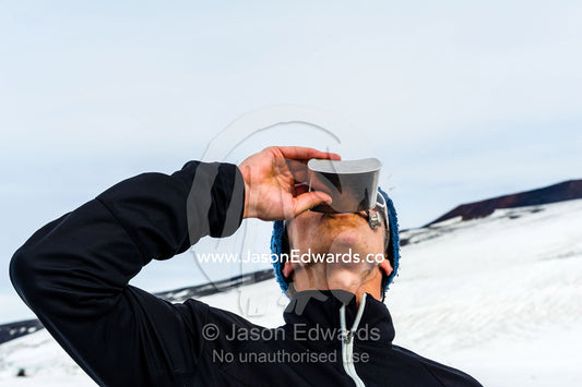 The winner of the Antarctic marathon celebrates with a drink from a hip flask. Ross Ice Shelf, Ross Island, Antarctica.