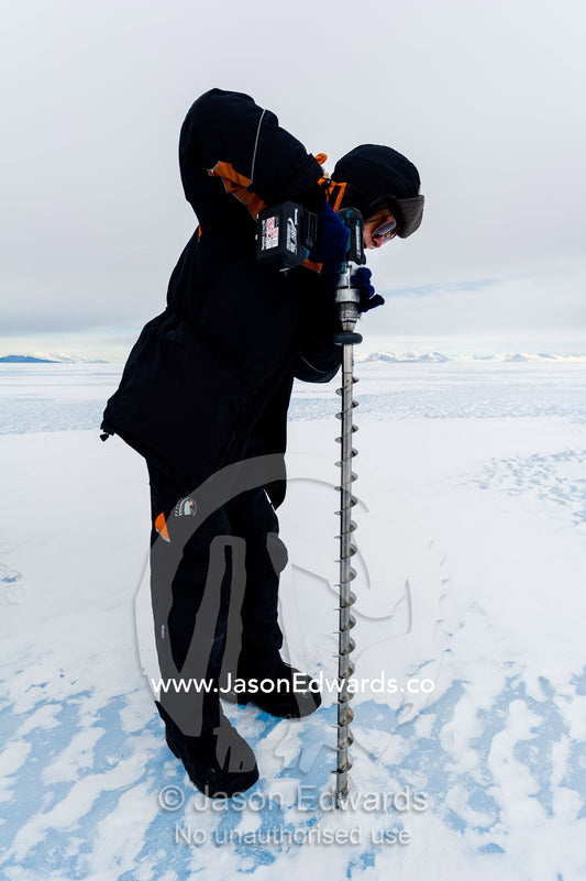 Testing the depth of sea ice for a Hagglund ice vehicle safety during the Antarctic summer. Turtle Rock, Erebus Bay, McMurdo Sound, Ross Island, Antarctica.