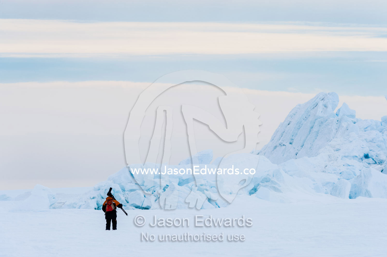A photographer carries his tripod and camera across the sea ice to photograph pressure ridges. Turtle Rock, Erebus Bay, McMurdo Sound, Ross Island, Antarctica.