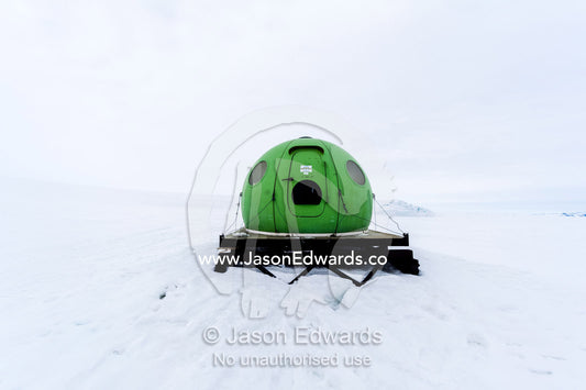 A bright green Apple hut also called an igloo satellite cabin, are light-weight field shelters hemispherical in shape. Castle Rock Road, Hut Point Peninsula, Ross Island, Antarctica.