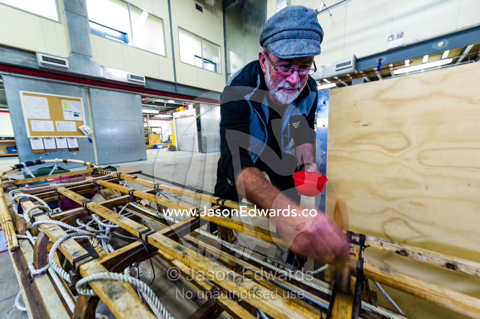 A volunteer oils and maintains antique timber sleds during the Antarctic summer. Scott Base, Pram Point, Hut Point Peninsula, Ross Island, Antarctica.