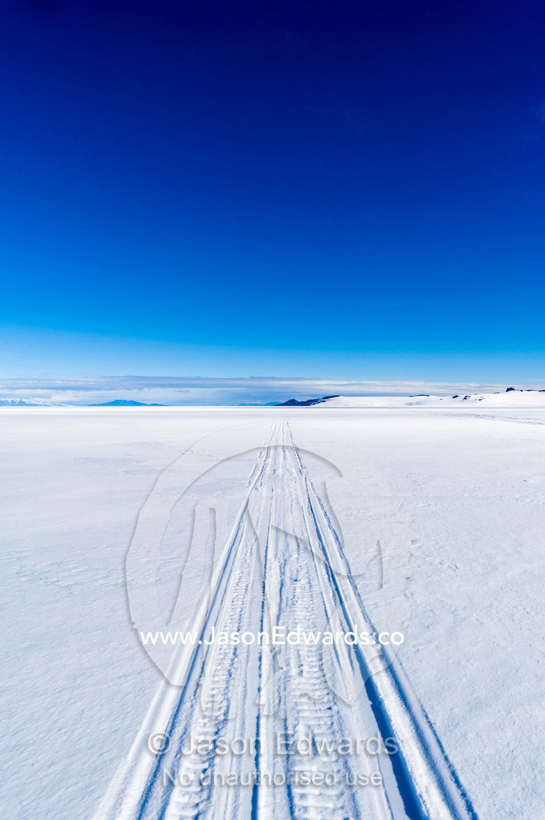 Skidoo tracks cross the frozen plain of the Ross Ice Shelf. Windless Bight, Ross Ice Shelf, Ross Island, Antarctica.