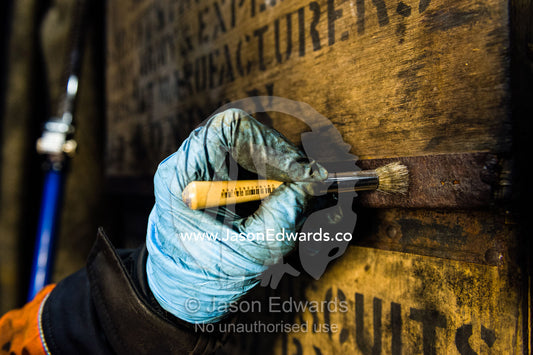 An expert from the Antarctic Heritage Trust working with a gentle brush and protective gloves to preserve a timber box in Discovery Hut. Discovery Hut, Hut Point, Ross Island, Antarctica.