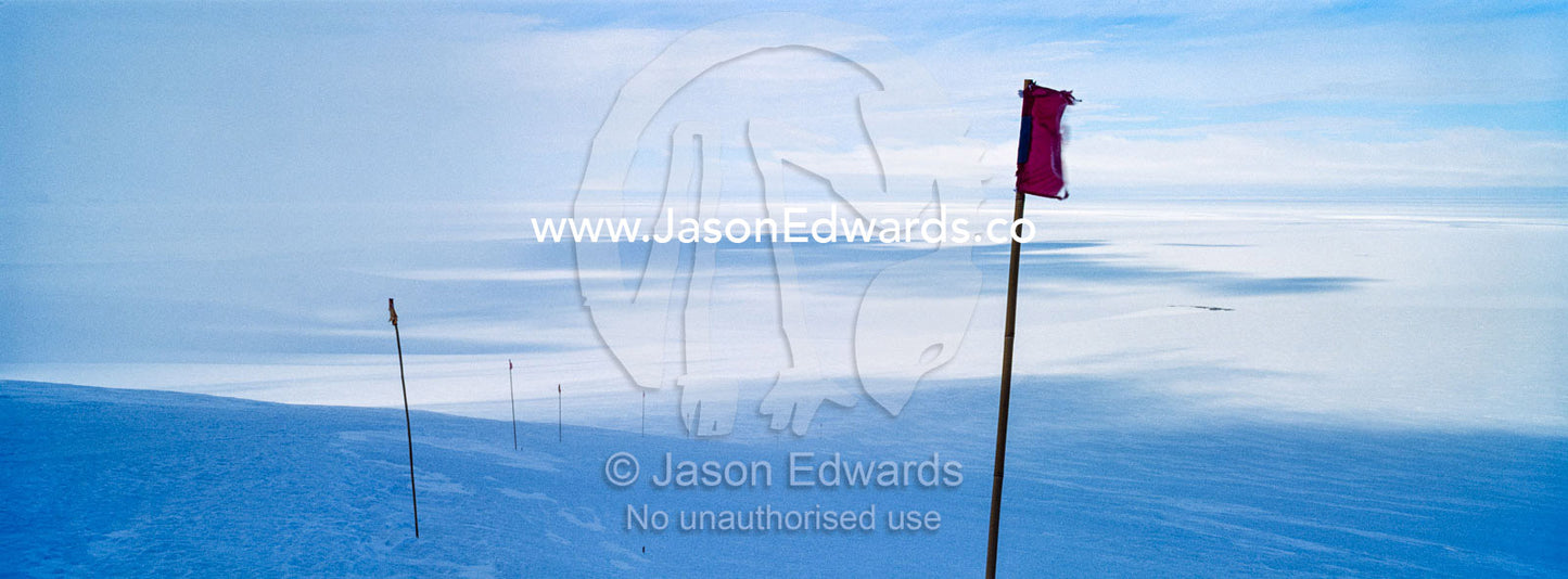 A red flag highlights a safe route across the sea ice. Castle Rock Road, Hut Point Peninsula, Ross Island, Antarctica.