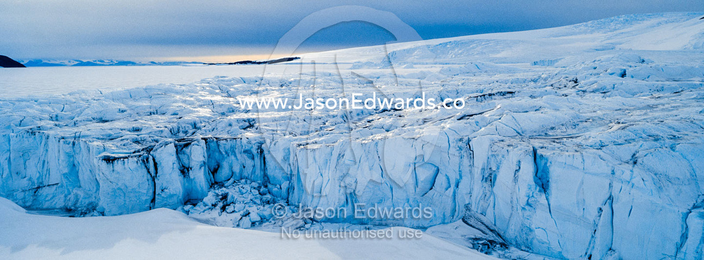 The sheer impregnable ice cliffs of a glacier tower over the frozen sea ice. Lands End, South Bay, Ross Island, Antarctica.