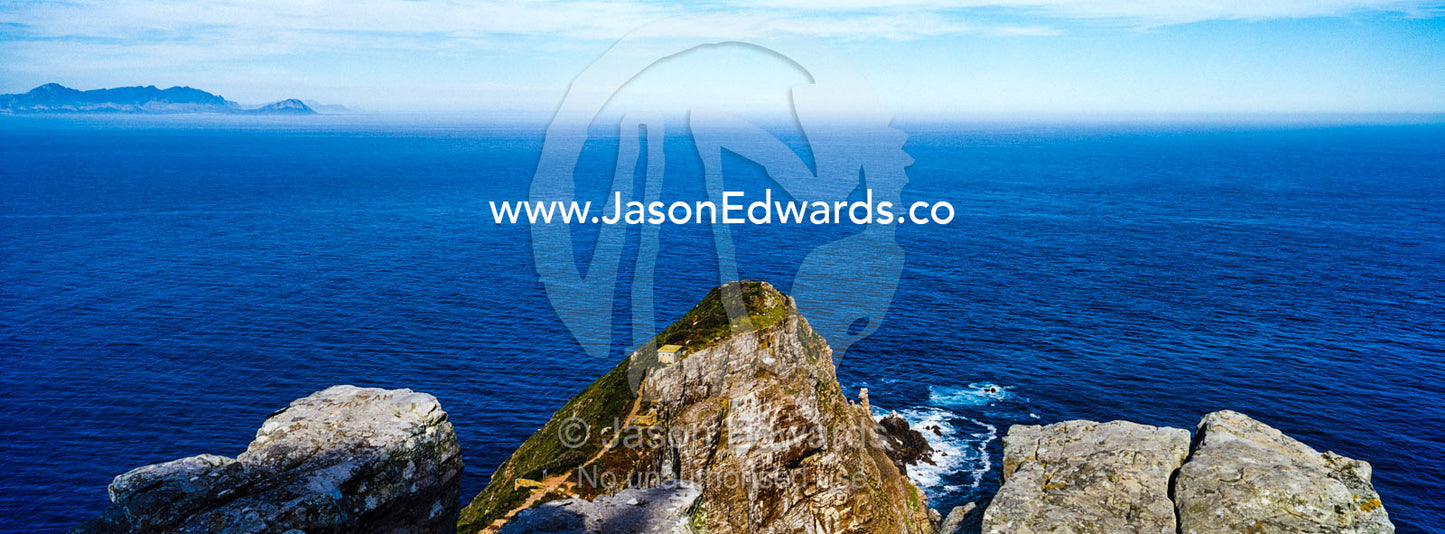 Brilliant blue ocean and rocky outcrops along the Cape of Good Hope. Hout Bay, Chapmans Peak Drive, Chapmans Peak Mountain Range, Cape Town, Western Cape, South Africa.