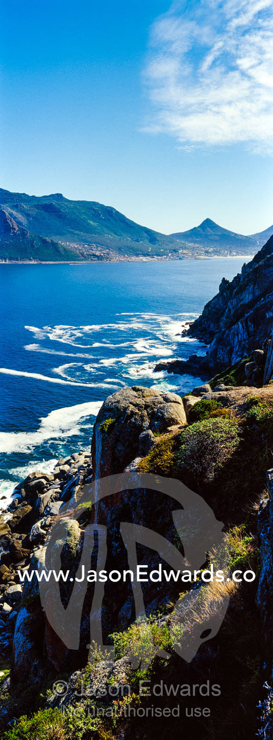 Wave foam trapped in currents along the base of coastal cliffs. Sentinel Peak, Hout Bay, Chapmans Peak Drive, Chapmans Peak Mountain Range, Cape Town, Western Cape, South Africa.