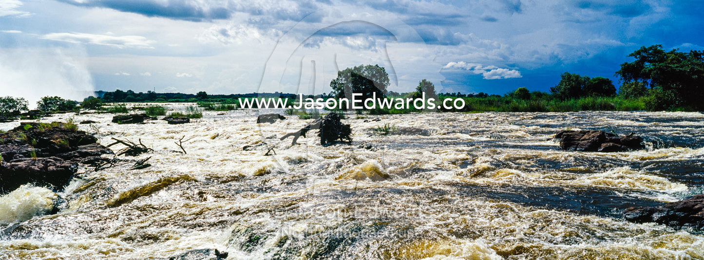 The raging current of the Zambezi River after heavy rain falls. Zambezi River, Victoria Falls, Mosi-oa-Tunya National Park, Zambia.