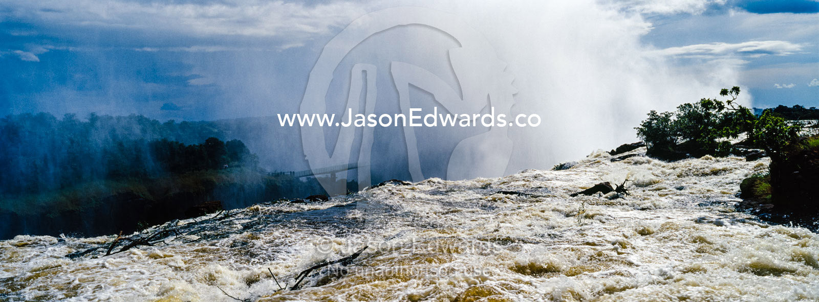 The rapids of the Zambezi River tumble over Victoria Falls sending up a plume of mist. Zambezi River, Victoria Falls, Mosi-oa-Tunya National Park, Zambia.
