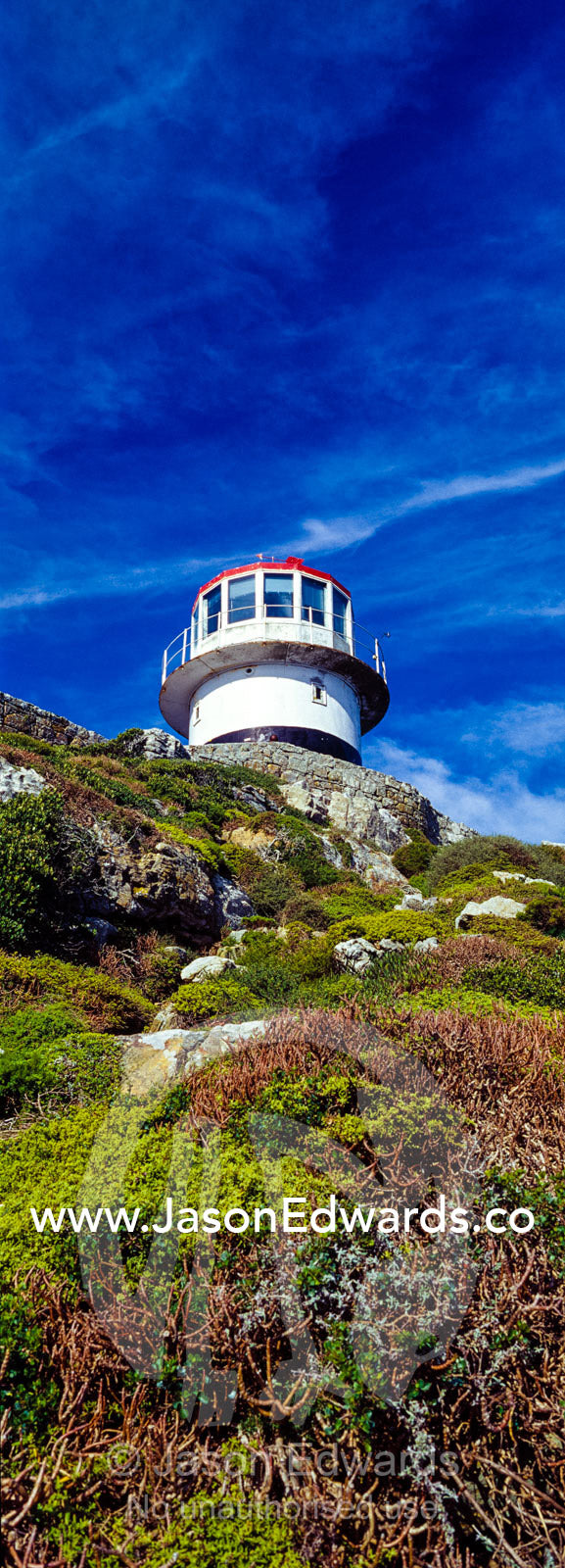 An antique lighthouse summits a cliff near the Cape of Good Hope. Cape of Good Hope, Cape Point, Table Mountain National Park, Cape Peninsula, South Africa.