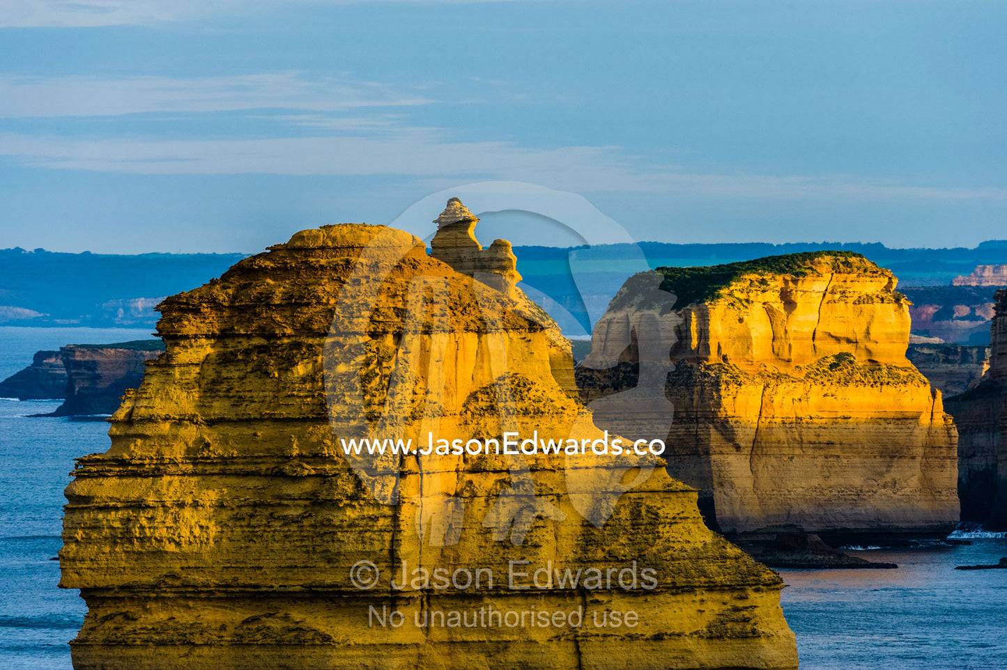 Dawn sunrays touch the sheer limestone cliffs and the Twelve Apostles pillars. Twelve Apostles, Port Campbell National, Great Ocean Road, Victoria, Australia.