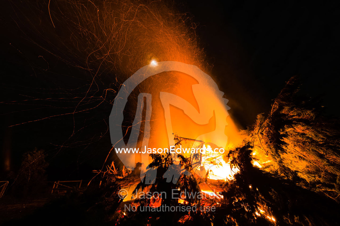 Flames and sparks fly into the air as a farmer burns surplus timber in a bonfire on his farm during winter. Bambra, Victoria, Australia.