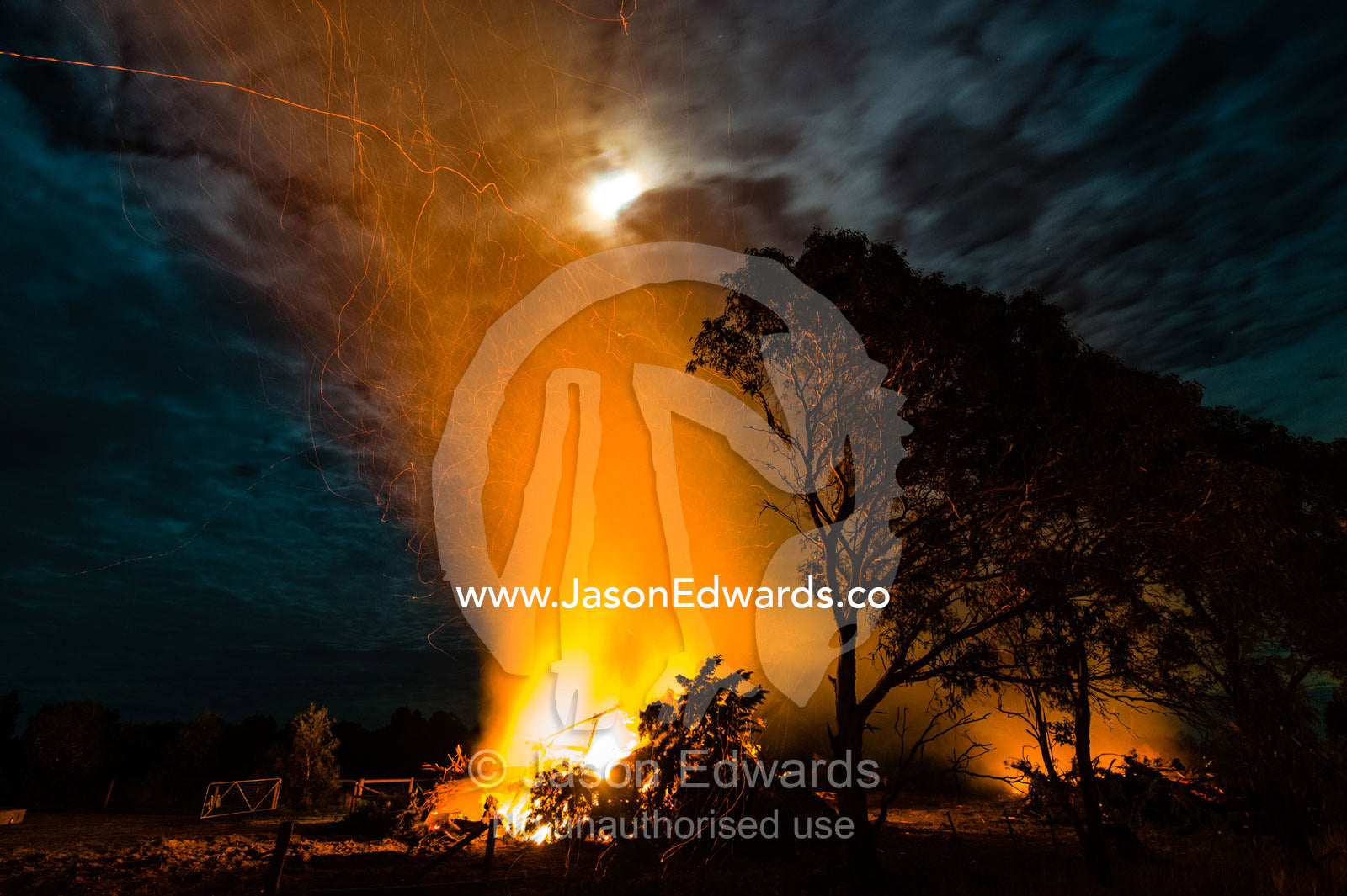 Flames and sparks fly into the air as a farmer burns surplus timber in a bonfire on his farm during winter. Bambra, Victoria, Australia.