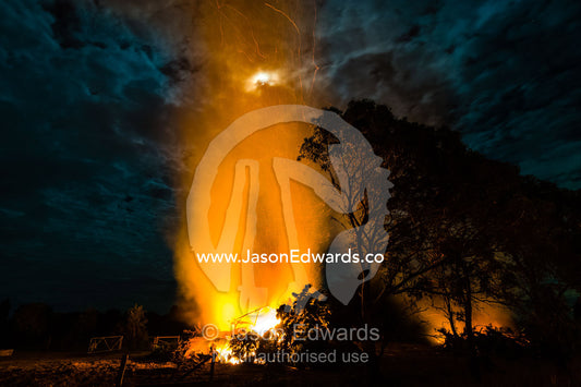 Flames and sparks fly into the air as a farmer burns surplus timber in a bonfire on his farm during winter. Bambra, Victoria, Australia.