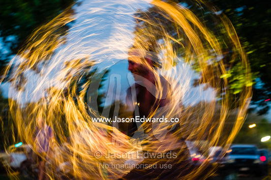 A fire performer dazzles the crowd at an open-air market by spinning a flaming baton. Mindil Beach Sunset Markets, Darwin, Northern Territory, Australia.