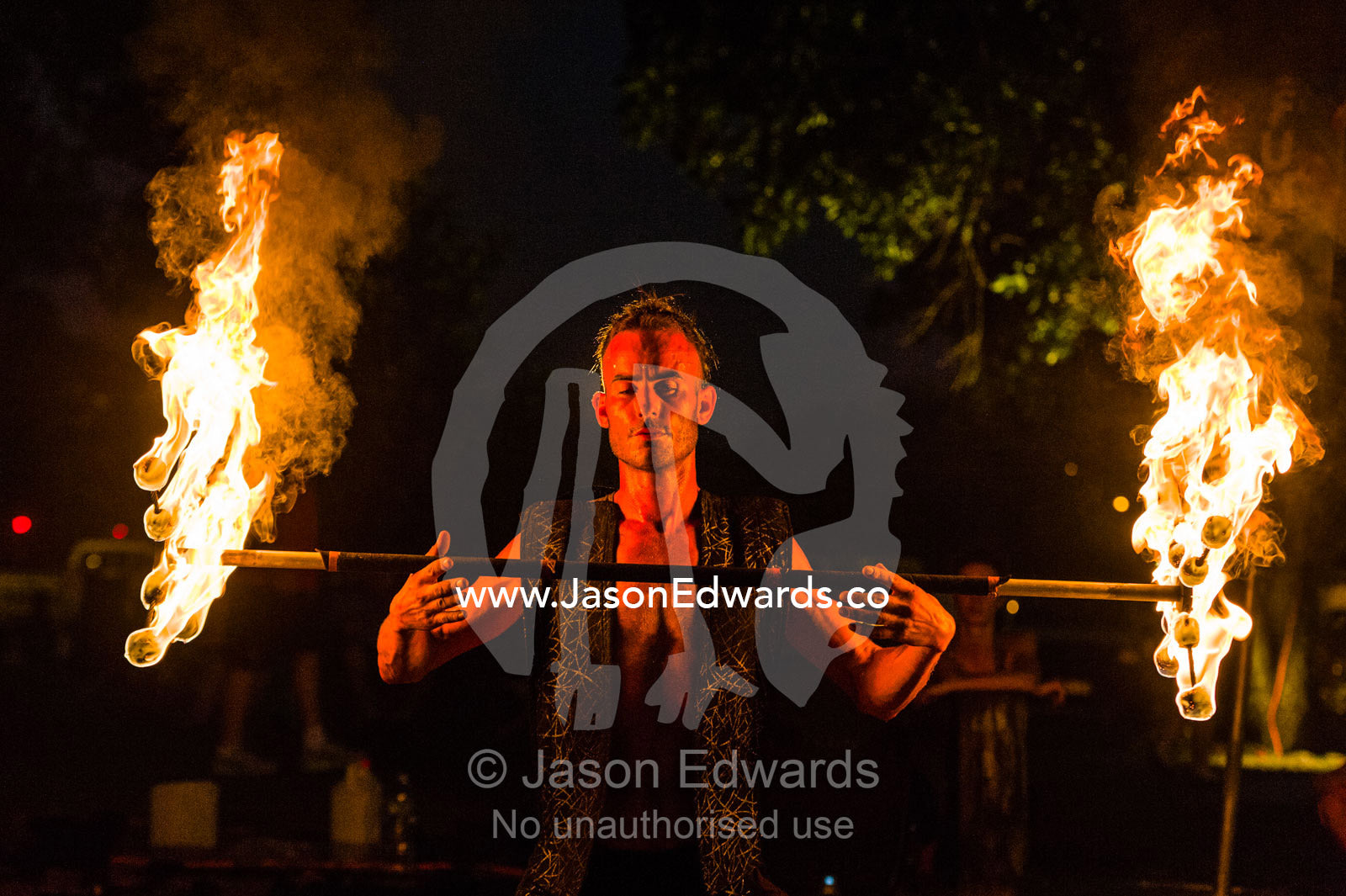 A fire performer dazzles the crowd at an open-air market by spinning a flaming baton. Mindil Beach Sunset Markets, Darwin, Northern Territory, Australia.