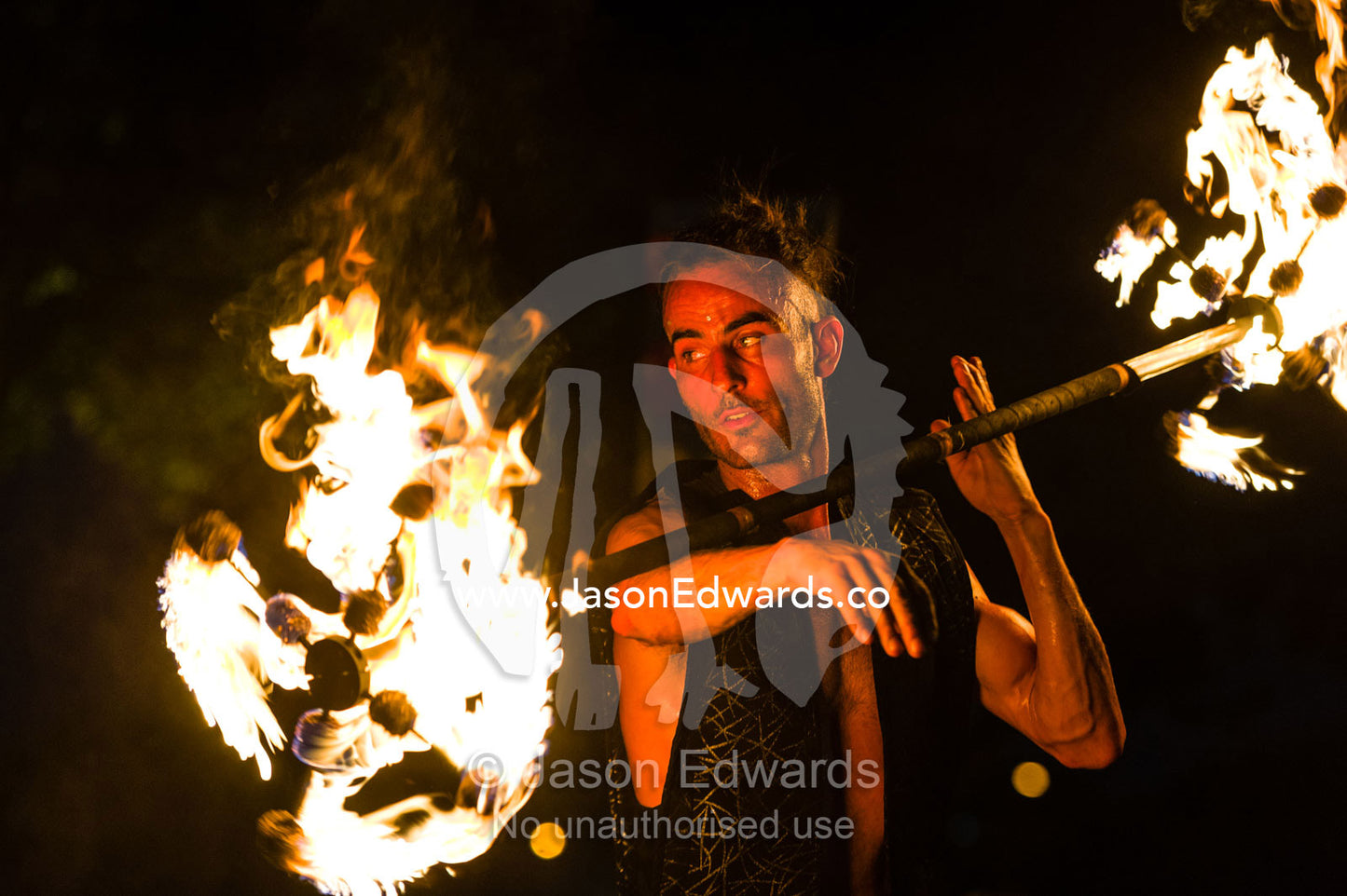 A fire performer dazzles the crowd at an open-air market by spinning a flaming baton. Mindil Beach Sunset Markets, Darwin, Northern Territory, Australia.