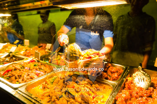 A chef prepares food in a take-away container at an open-air market. Mindil Beach Sunset Markets, Darwin, Northern Territory, Australia.