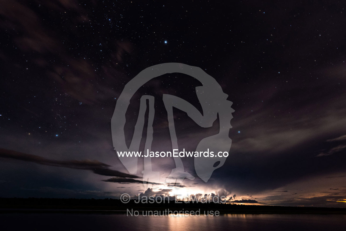 Lightning strikes a floodplain at night beneath a star-filled sky. Chobe River, Chobe National Park, Botswana.