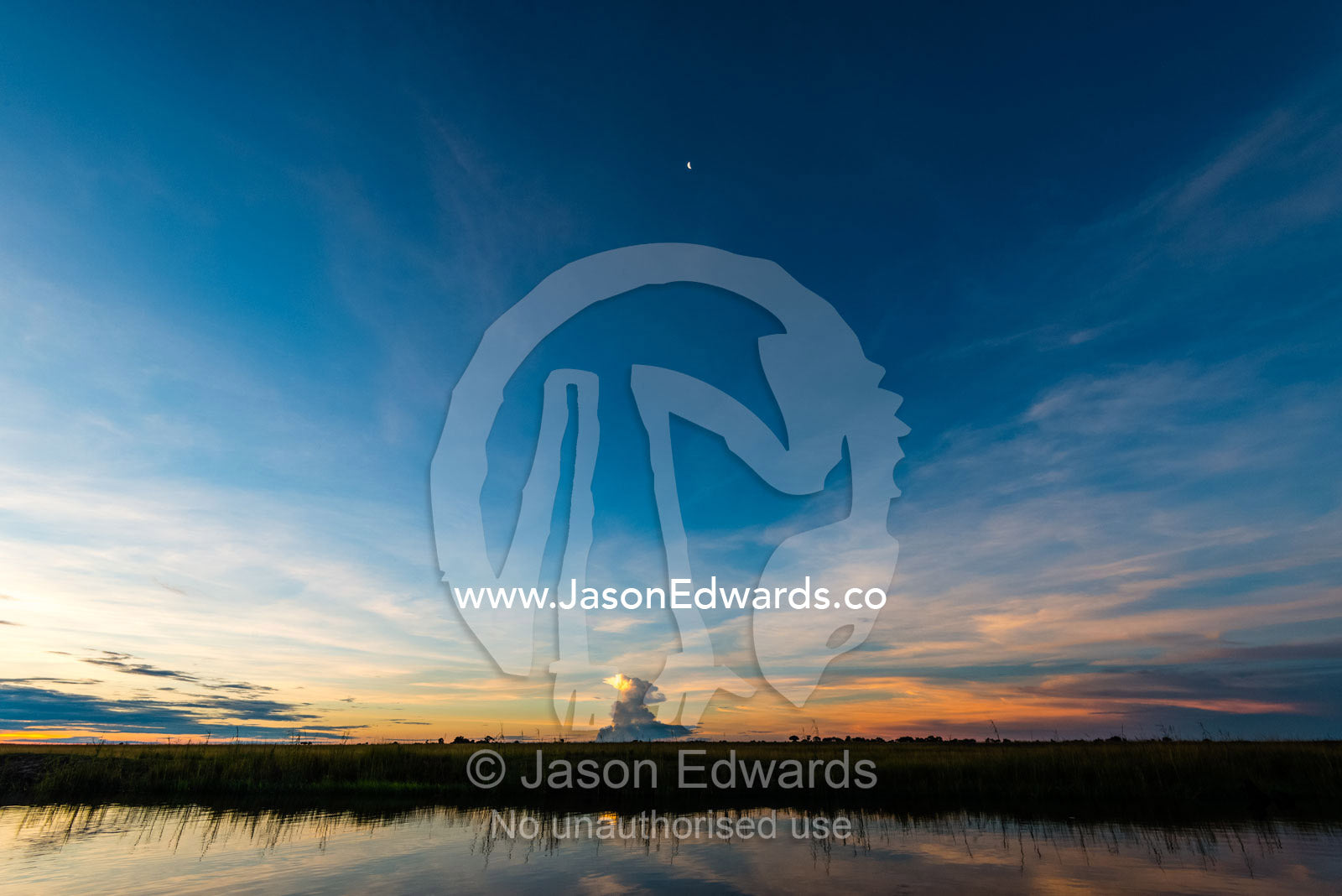 The sunset afterglow sweeps across a wide African sky above a wetland. Chobe River, Chobe National Park, Botswana.
