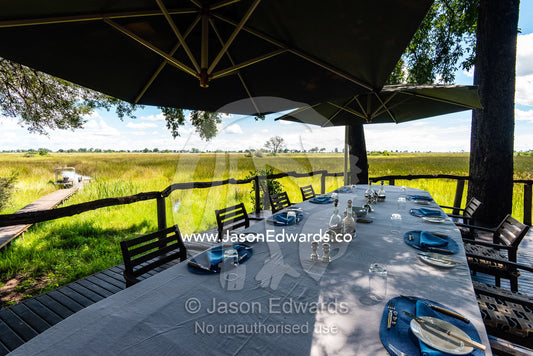 A dining table at a safari camp set for a lunch meal overlooking a wetland. Duba Plains Camp, Ngamiland West, Botswana.