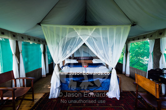 A mosquito net around a bed in a luxurious safari camp tent. Duba Plains Camp, Ngamiland West, Botswana.