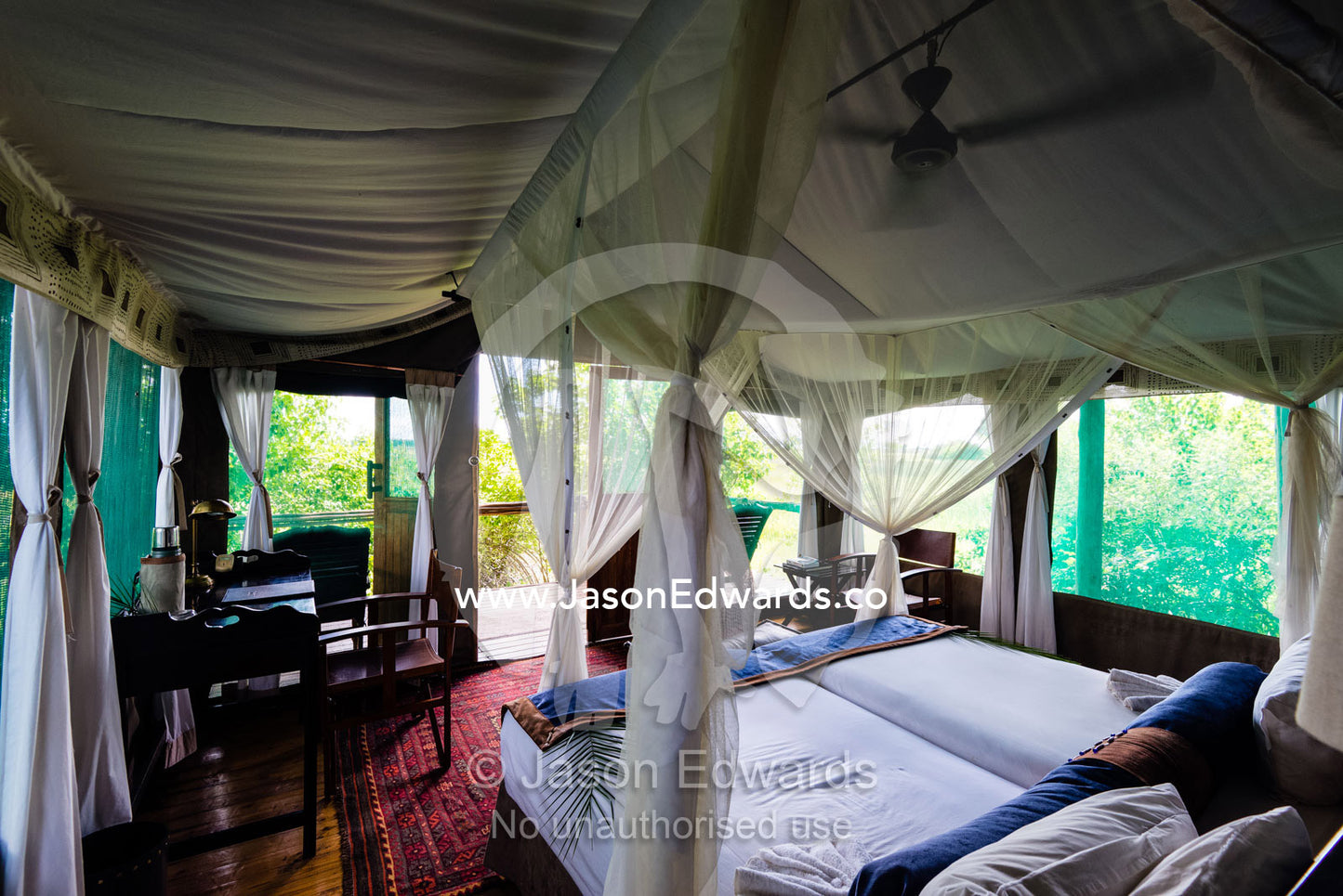 A mosquito net around a bed in a luxurious safari camp tent. Duba Plains Camp, Ngamiland West, Botswana.