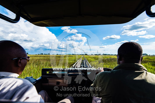Safari guides driving a 4wd across a floating bridge on a floodplain. Duba Plains Camp, Ngamiland West, Botswana.