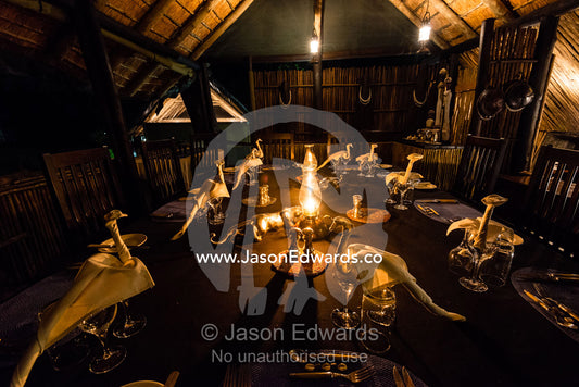 An elegant lantern-lit dining table set for a meal in a safari camp. Duba Plains Camp, Ngamiland West, Botswana.