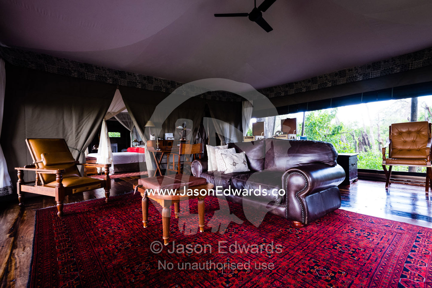 A leather sofa and antique furniture in the sitting room of a luxurious tented safari camp. Zarafa Camp, Zibadianja Lagoon, Savute Channel, Linyanti, Botswana.