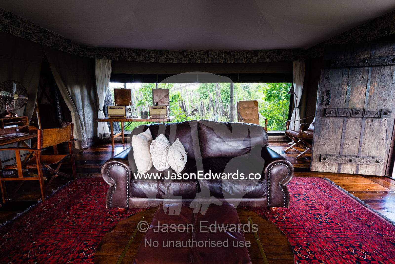 A leather sofa and antique furniture in the sitting room of a luxurious tented safari camp. Zarafa Camp, Zibadianja Lagoon, Savute Channel, Linyanti, Botswana.