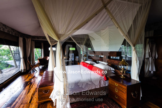 A mosquito net around a bed in a luxurious safari camp tent. Zarafa Camp, Zibadianja Lagoon, Savute Channel, Linyanti, Botswana.
