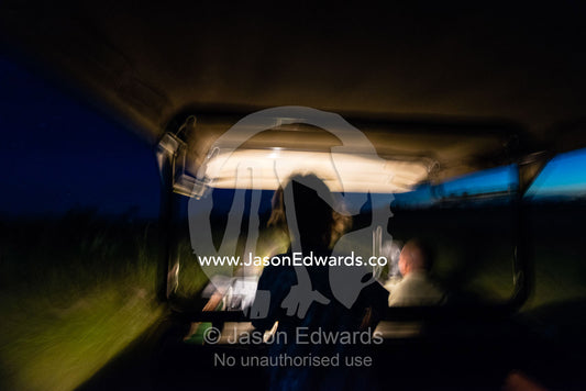 A boy searches for wildlife with a spotlight on a 4wd night safari game drive. Selinda Reserve, Linyanti Region, Northern Botswana.