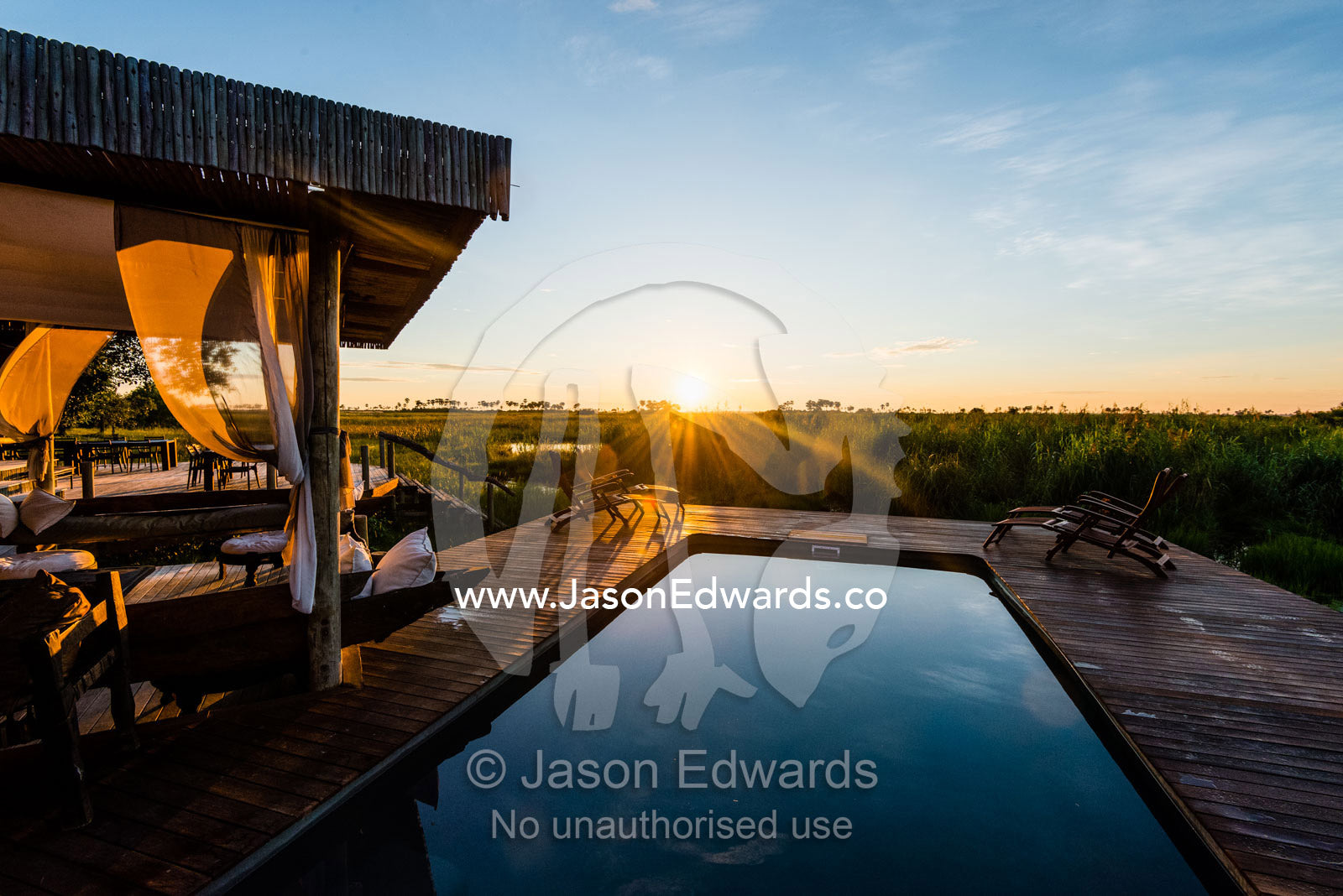 A swimming pool overlooking a wetland in a luxury safari camp at dawn. Selinda Camp, Selinda Reserve, Linyanti Region, Northern Botswana.