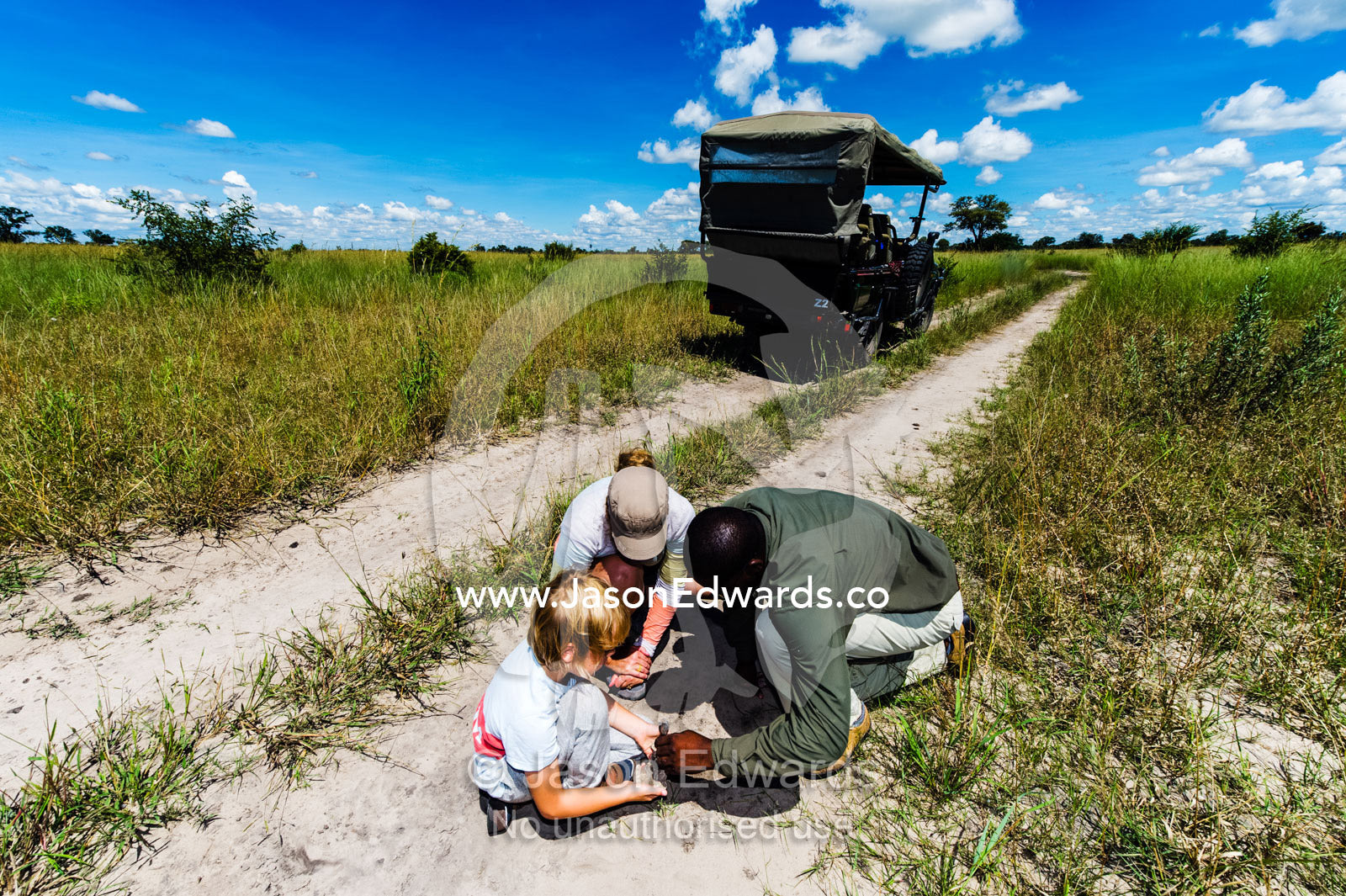 An African safari guide teaching a boy and his mother to make plaster casts of animal tracks. Selinda Reserve, Linyanti Region, Northern Botswana.