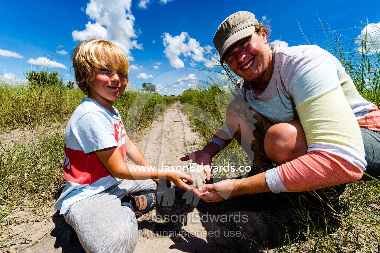 A mother and son with a plaster cast of an animal track they made in the sand. Selinda Reserve, Linyanti Region, Northern Botswana.